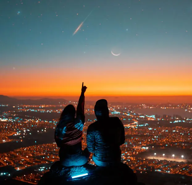 Couple sitting together and pointing at the stars.
