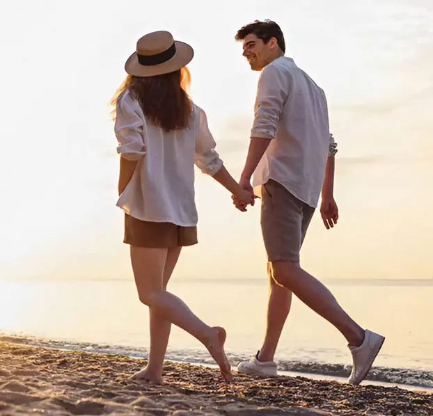 Couple walking hand in hand along the beach, representing love, relationships, and emotional connection.