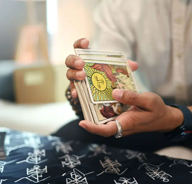 Hands shuffling a deck of tarot cards.